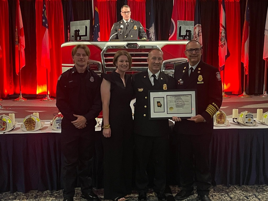 Image showing 🚒Congratulations Instructor Brian Croft! 🏆 Claxton High School and The DEN are incredibly proud to send a massive congratulations to our firefighting instructor and Evans County Fire and Rescue Deputy Chief, Brian Croft!  Deputy Chief Croft was recently awarded the prestigious Georgia Chief Fire Officer Certification at the Georgia Association of Fire Chiefs Leadership Conference in Savannah, GA. This certification represents the highest level of professional management and leadership excellence in the fire service.  Sharing in the proud moment at the conference were his wife, Mandy, and their son, Bryson. Having Bryson there was an extra special touch, as he actually completed the firefighting program under his dad's instruction through The DEN at CHS and is now serving as a firefighter in Bulloch County.  Since the firefighting program's inaugural school year in 2020-2021, Deputy Chief Croft has been a vital teacher, mentor, and role model for countless students looking to serve our local communities. We appreciate your hard work, your high standards, and your dedication to shaping the next generation of first responders.  Thank you for all you do, Deputy Chief Croft! 🐯🖤💛  #TheDEN #FirefightingInstructor #ChiefFireOfficer #EvansCountyFireAndRescue #CTAE #TigerPride #FirstResponders