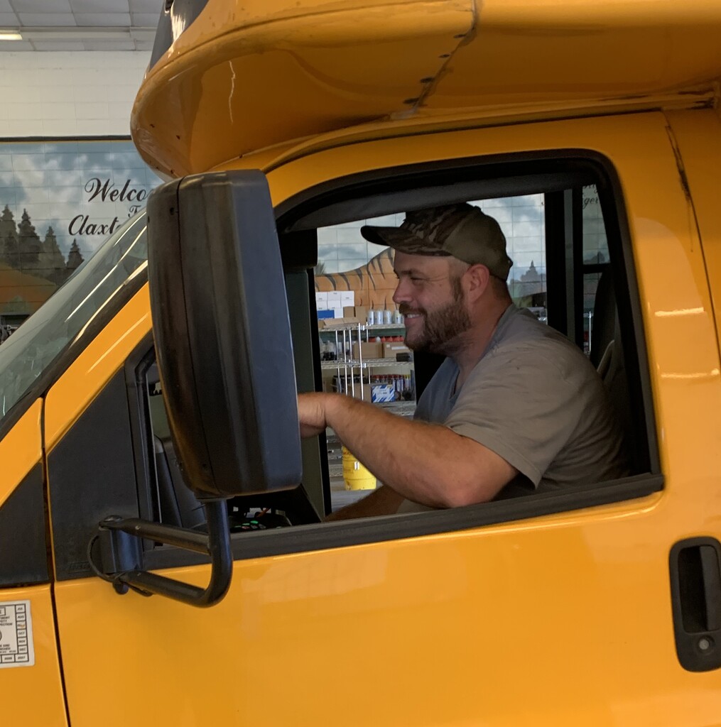 Bus Shop Mechanic, Kyle Whitfield, pictured in the driver's seat of a bus.