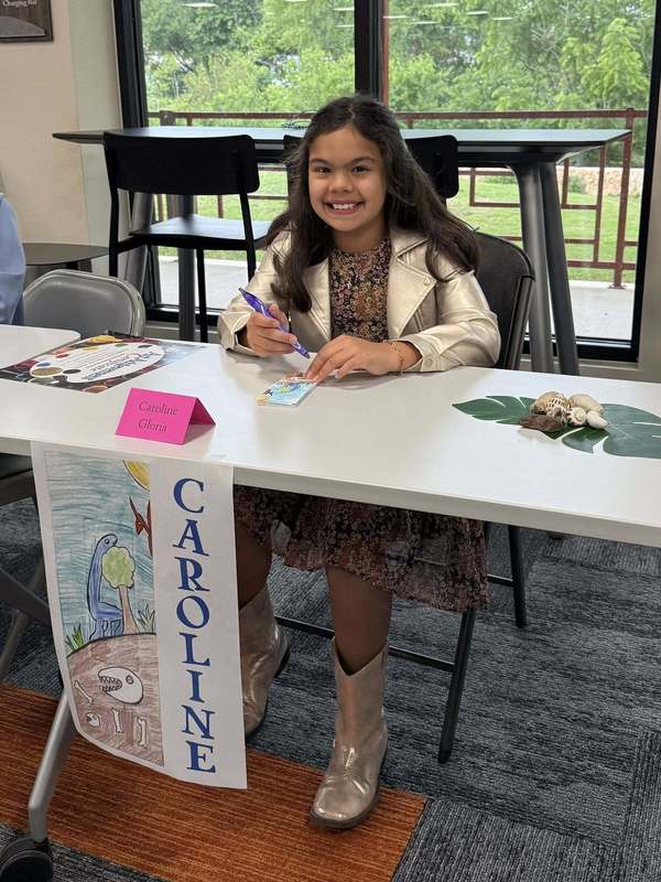 Caroline signing bookmarks, image