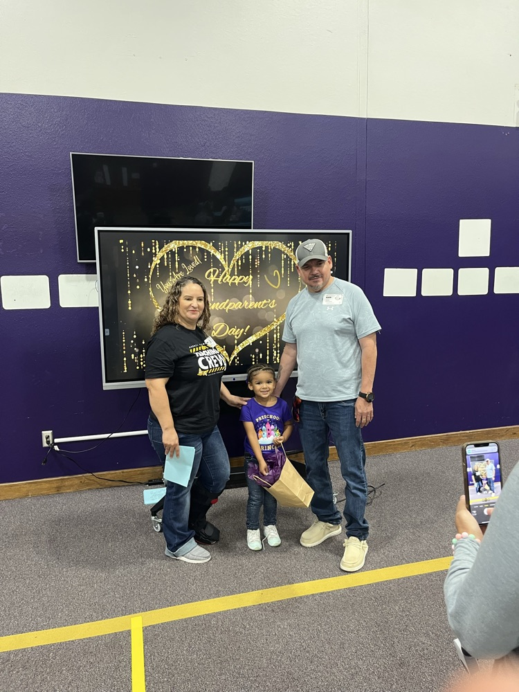 Grandparents and grand friends taking a picture in front of the heart backdrop on the board.