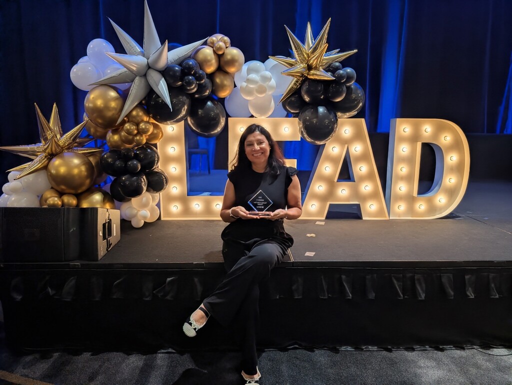 Mrs. Rayman holding her award on stage.