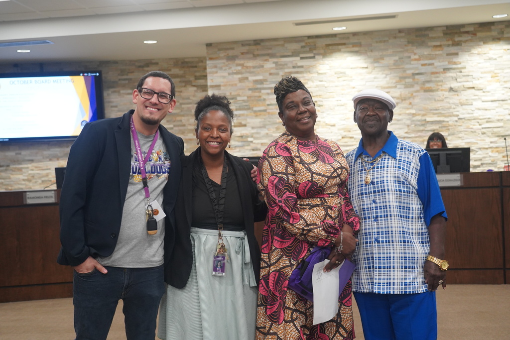 Everman ISD+ picture of staff member and husband with E.Ray Elementary principal and staff celebrating spotlight award