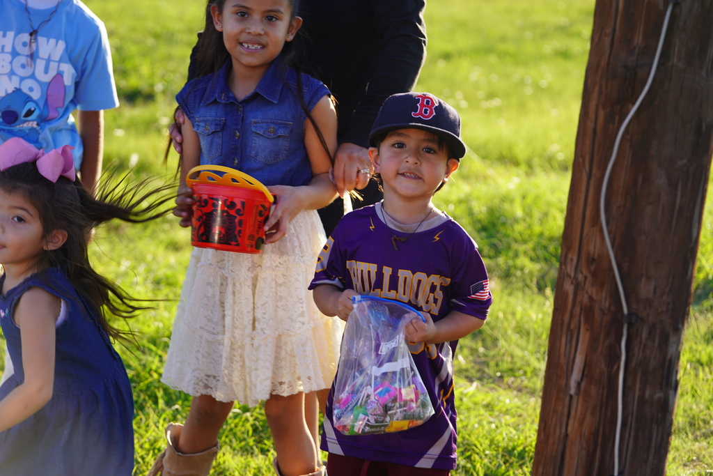   three kids smiling with bags and buckets of candy 