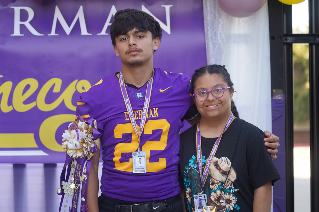 A boy and a girl stand together, both wearing lanyards. The boy wears a football jersey with the number 22 on it.