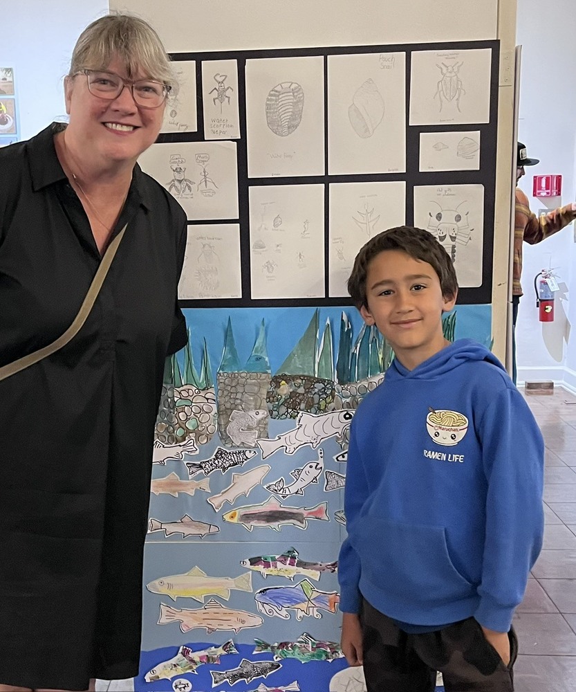 A student and a teacher smiling in front of an art exhibit.