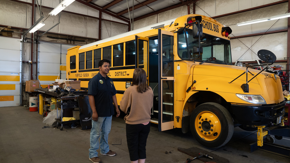 Two people standing in front of a school bus