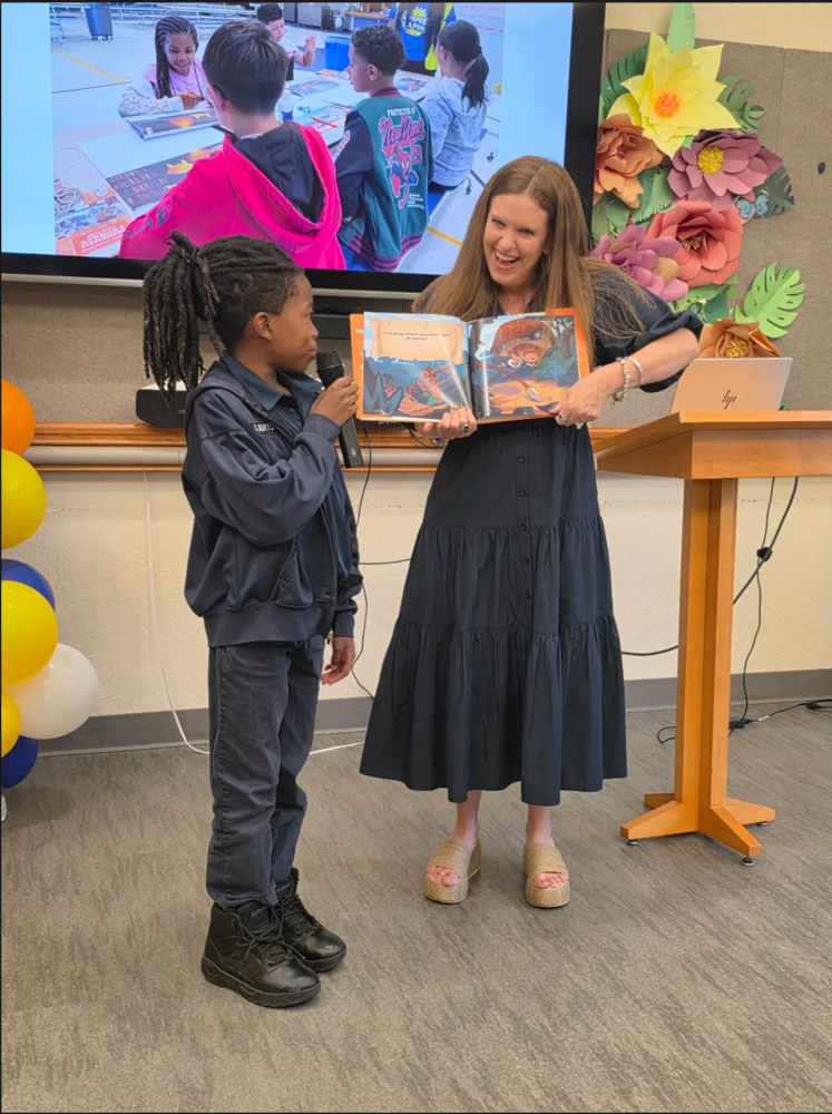 Principal of the Expanded Learning Opportunity Program posing with a student with a book in hand