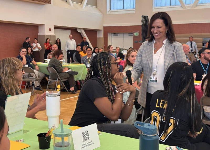 Superintendent smiling holding a microphone up to a new teacher to speak at the premier start event
