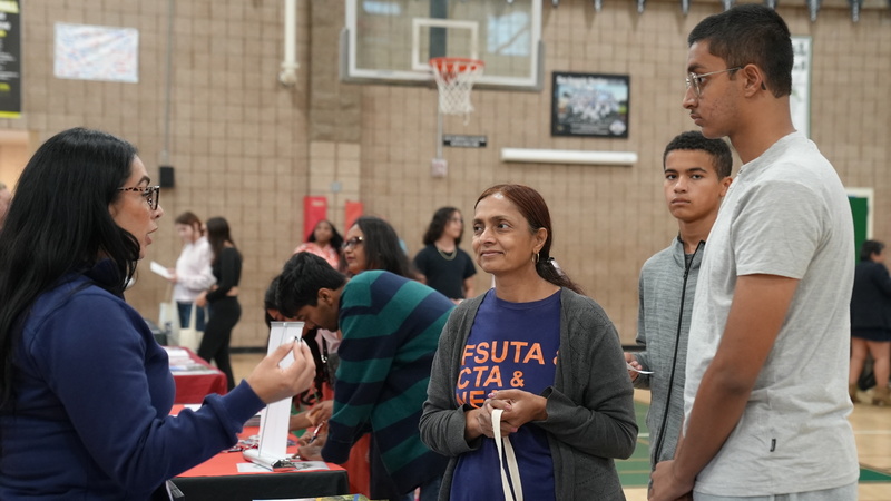 Parent and student speaking to one of the representatives at the college fair