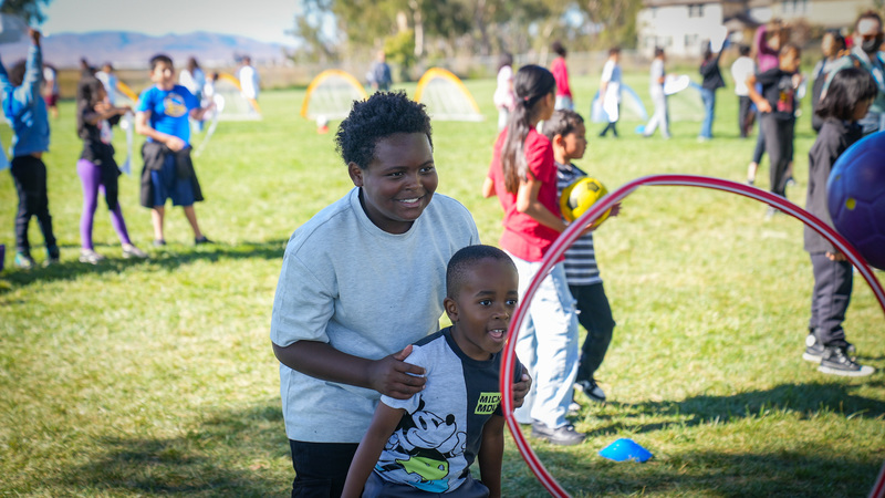Two students playing by throwing a ball through a hoola hoop.
