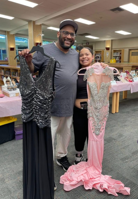 A girl and her dad smiling holding Prom Dresses