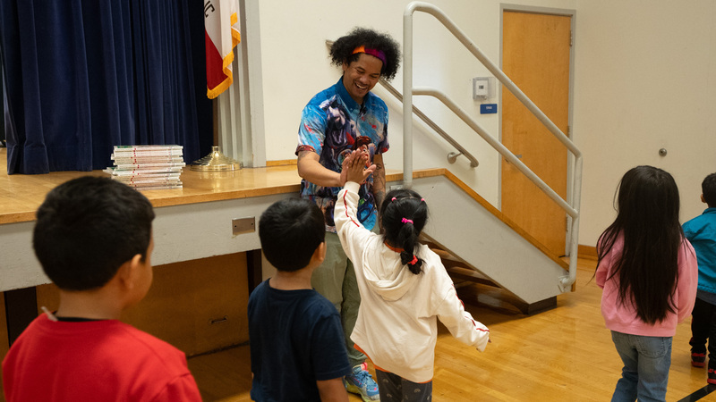 Mychal Threets giving a high-five to an student