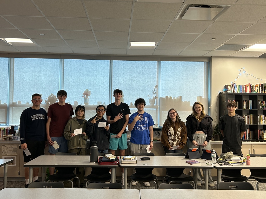 9 students standing holding cards