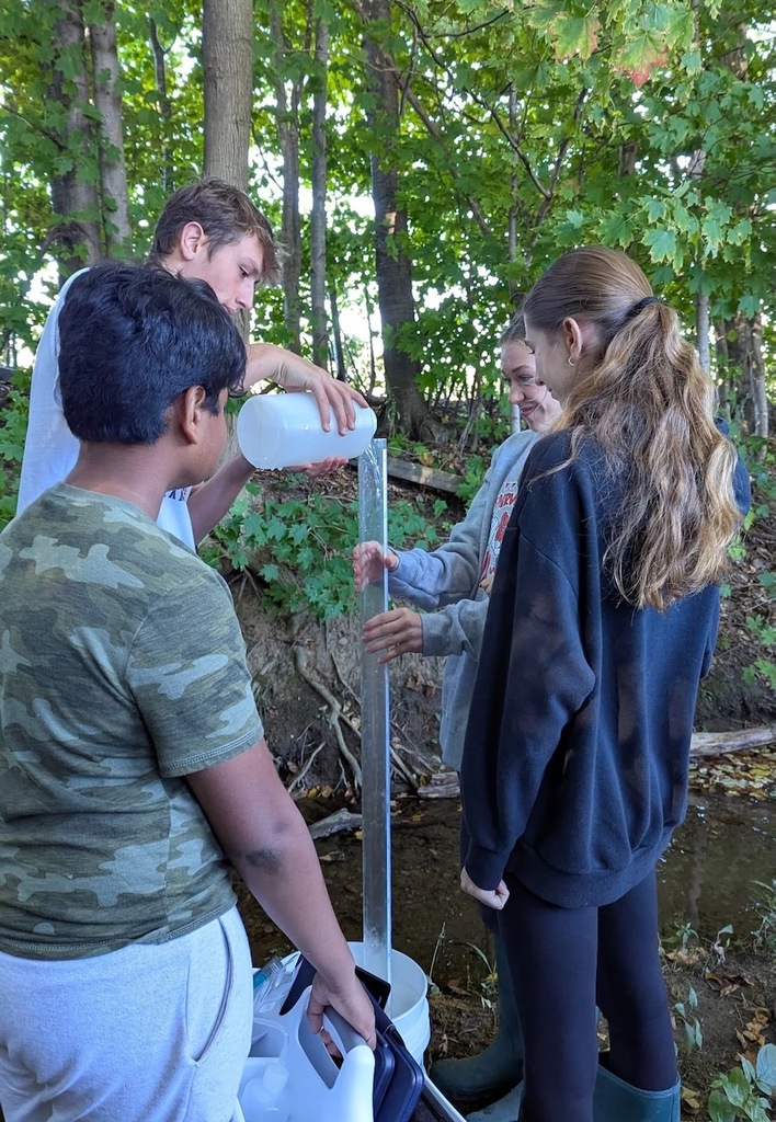 4 students filling up a long cylinder with water