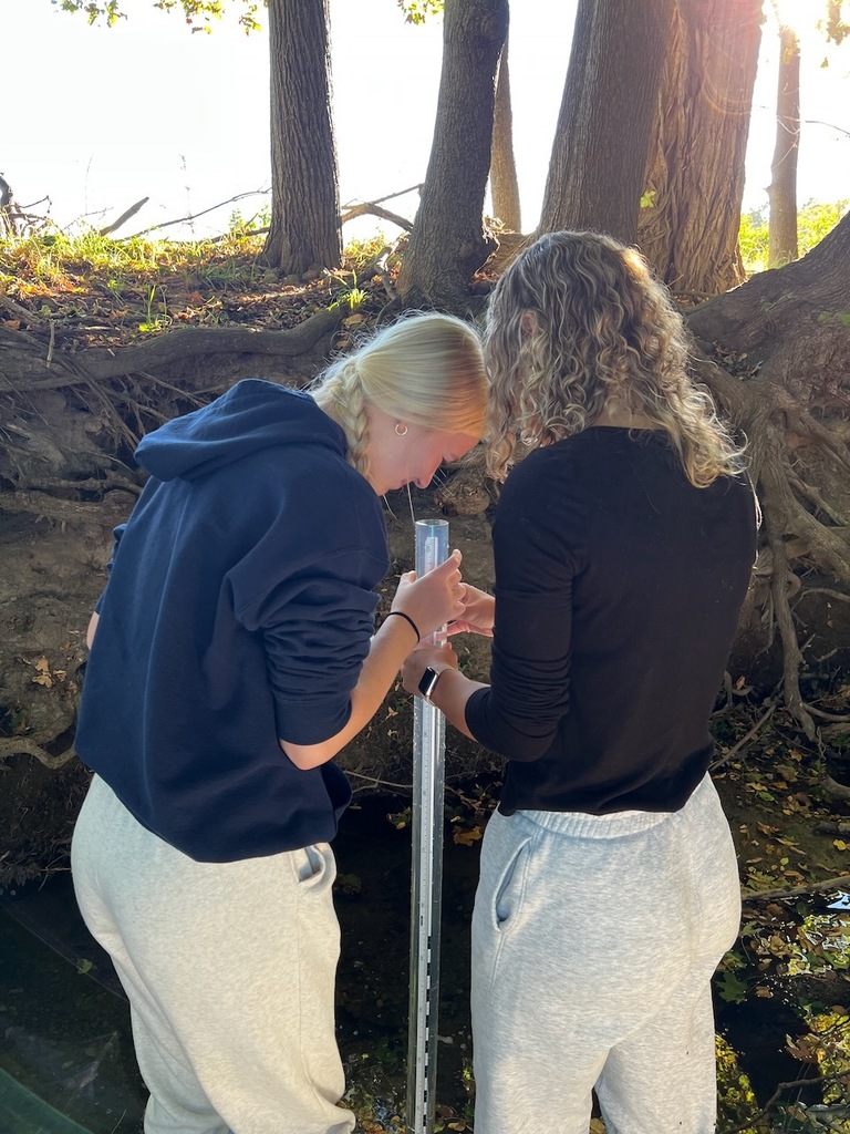 2 students looking into a long cylinder