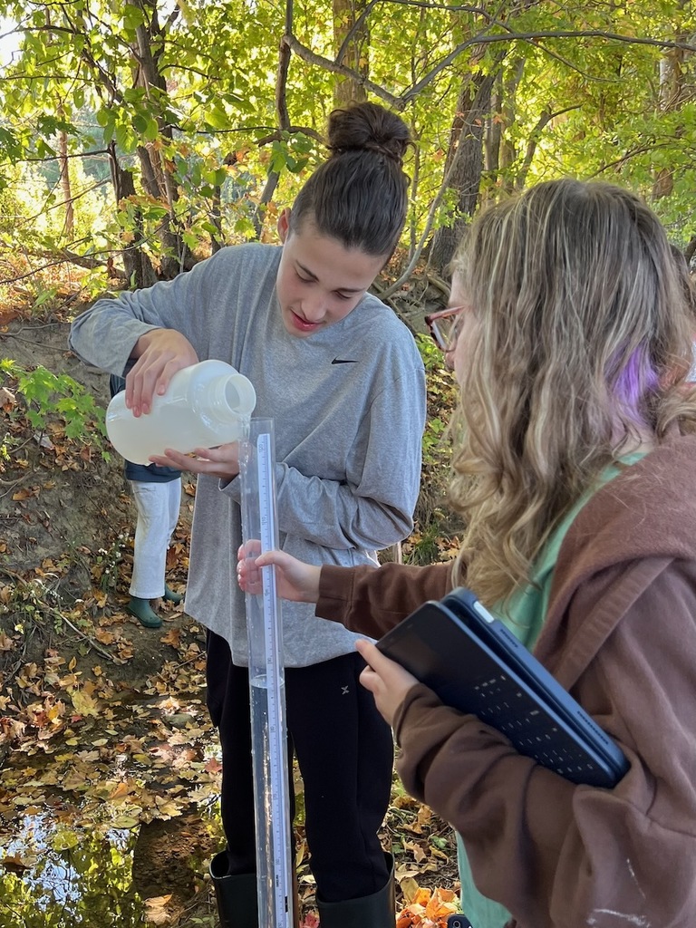 two students filling up a cylinder with water