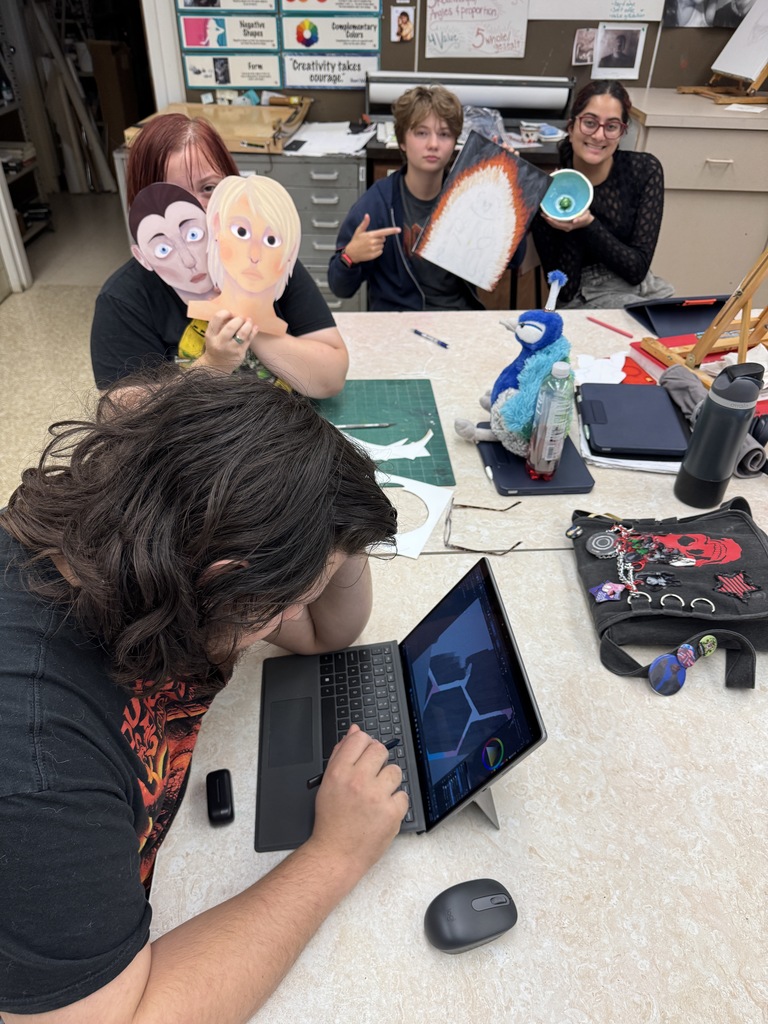 3 students holding art projects
