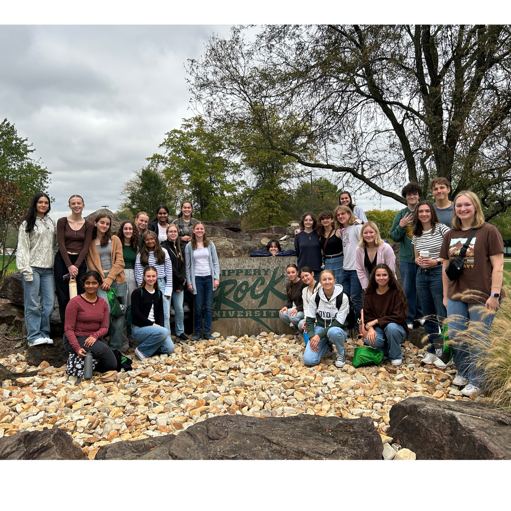 Group of students standing in front of the Slippery Rock sign.