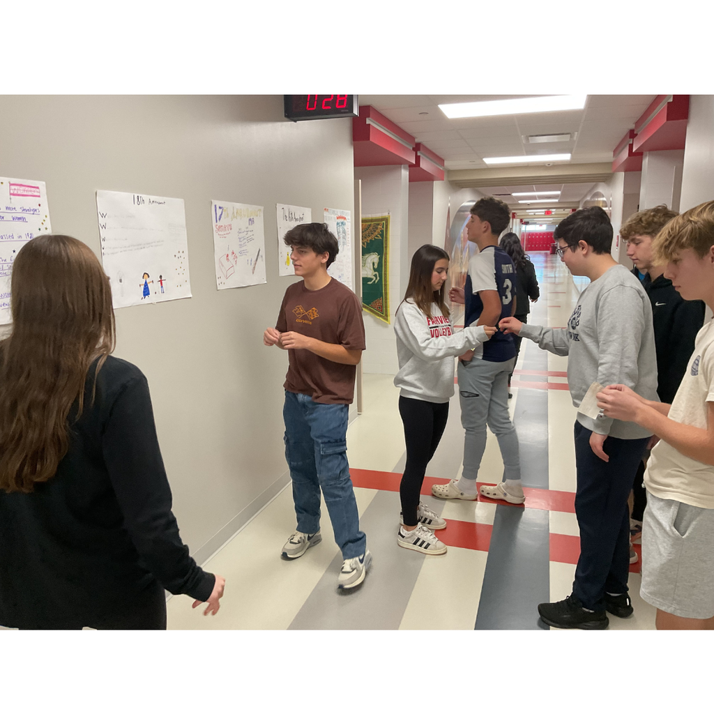 7 students looking at posters on a wall