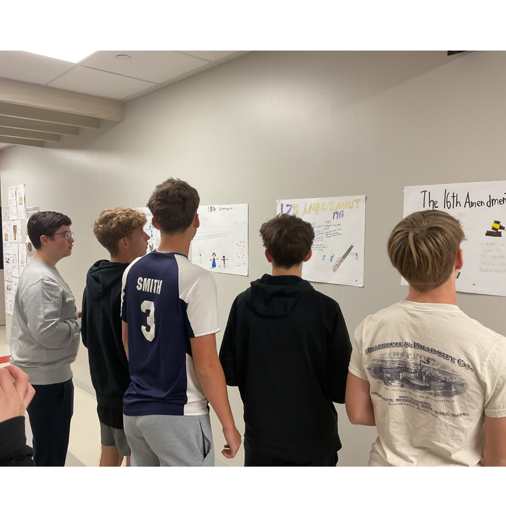 5 students looking at posters on a wall