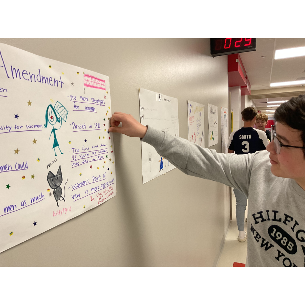 3 students looking at posters on a wall