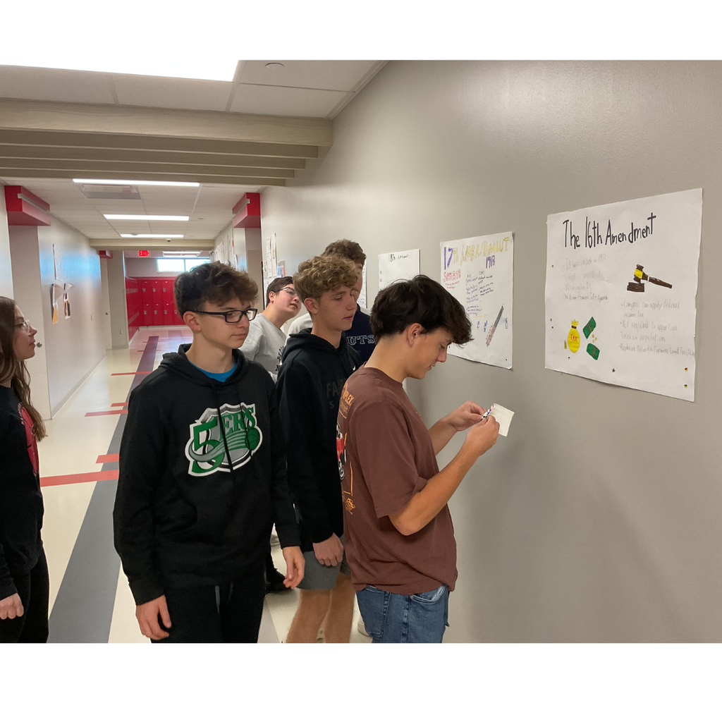 5 students looking at posters on a wall