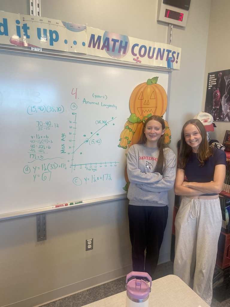 2 students standing next to their finished math problem