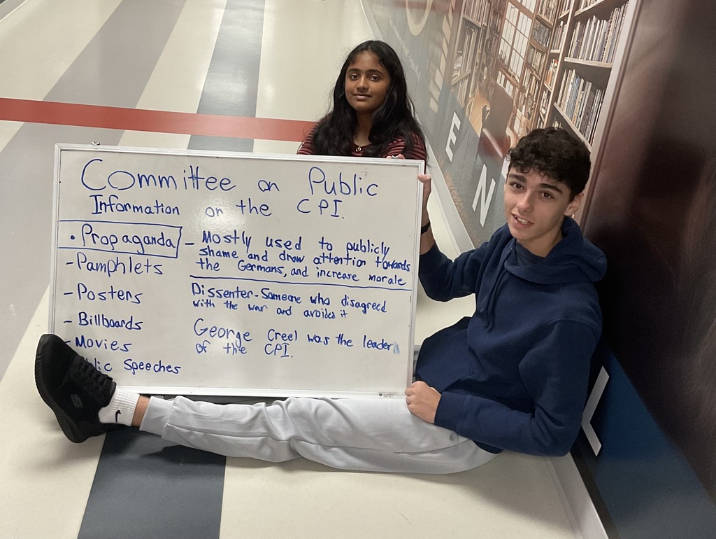 2 students holding a board about CPI