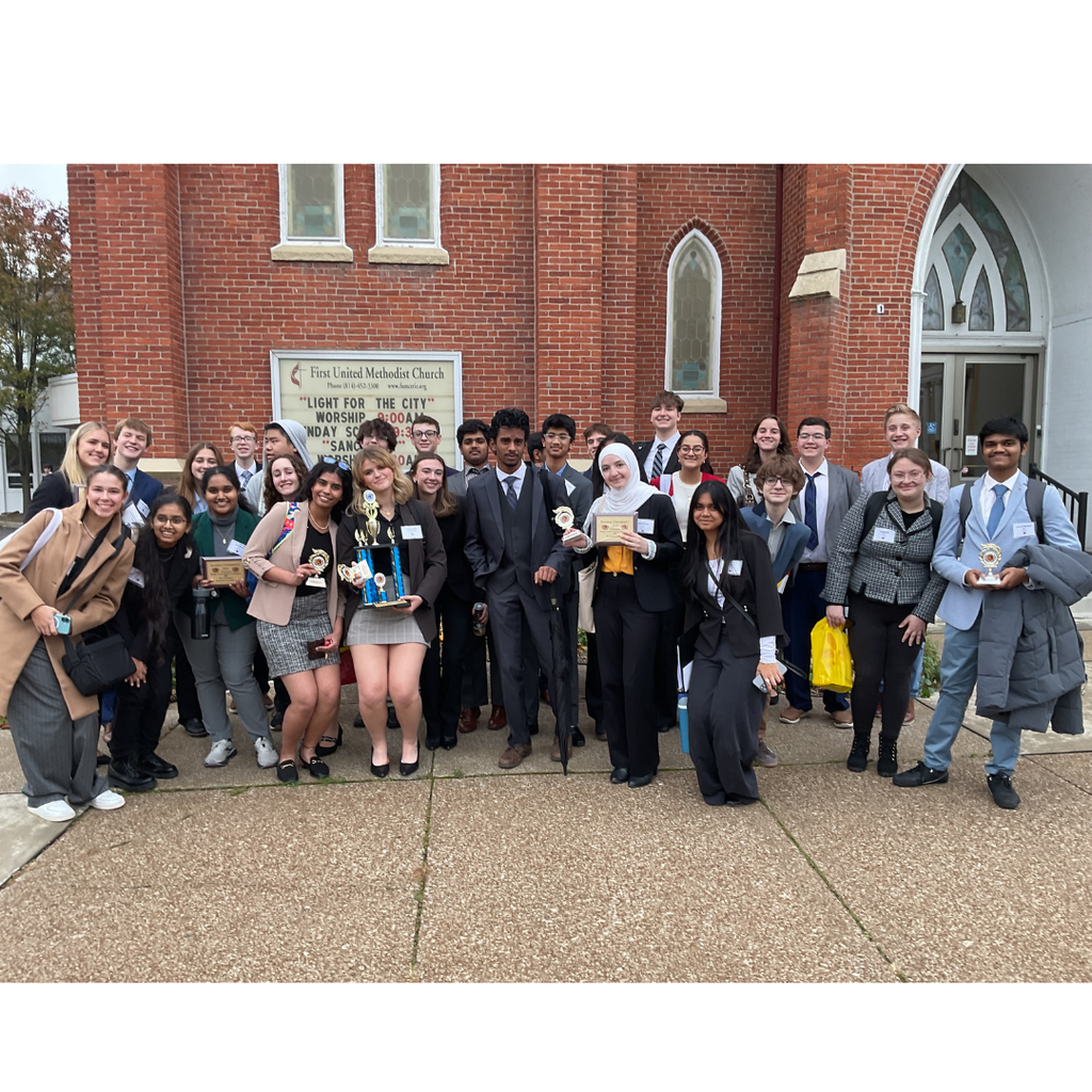 group of students standing with multiple trophies.