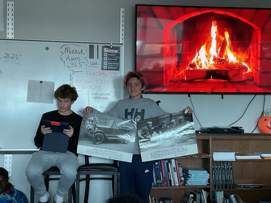 2 students presenting in front of a fireplace on a tv