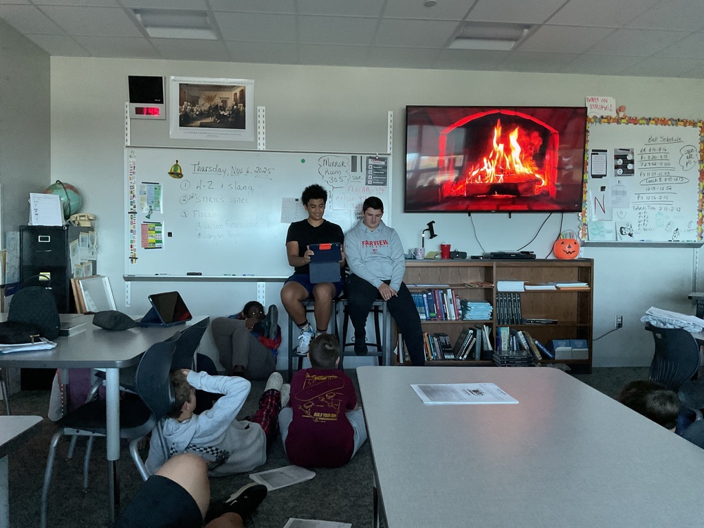 2 students presenting in front of a fireplace on a tv