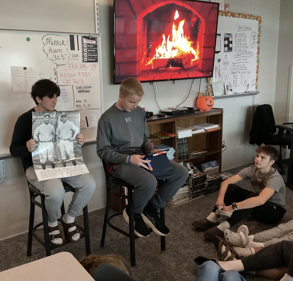 2 students presenting in front of a fireplace on a tv