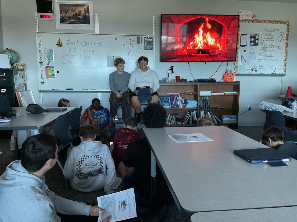 2 students presenting in front of a fireplace on a tv