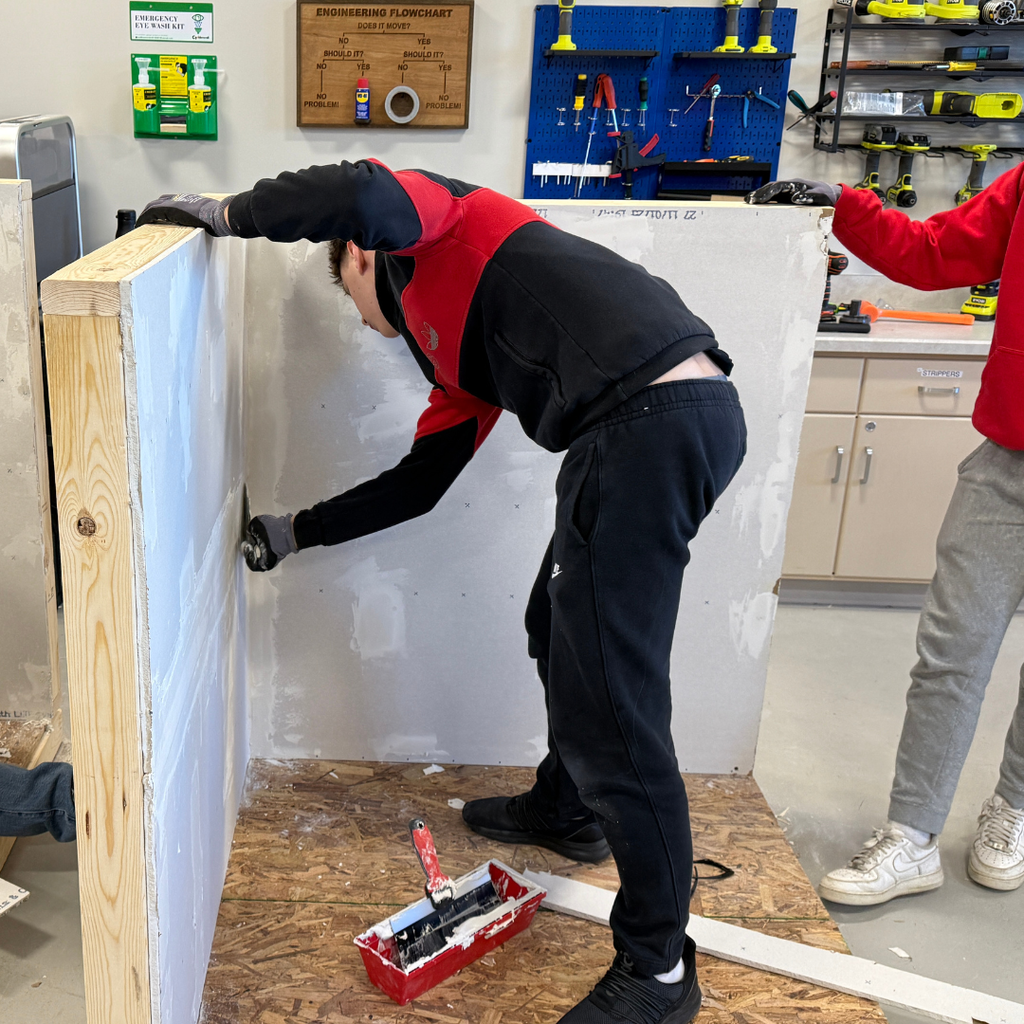 One student mudding a wall