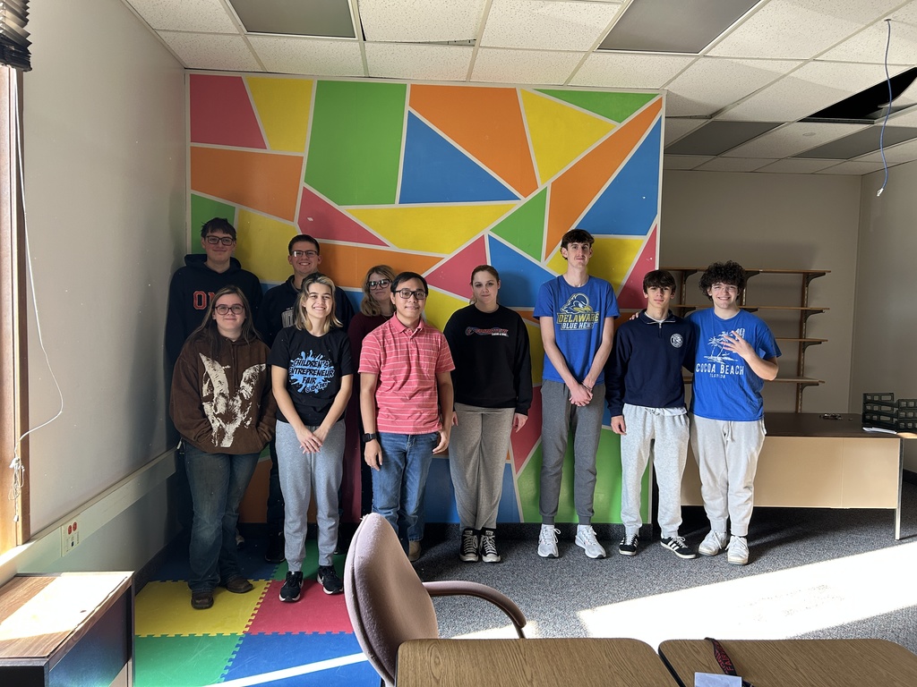group of students standing in front a of a colorful wall