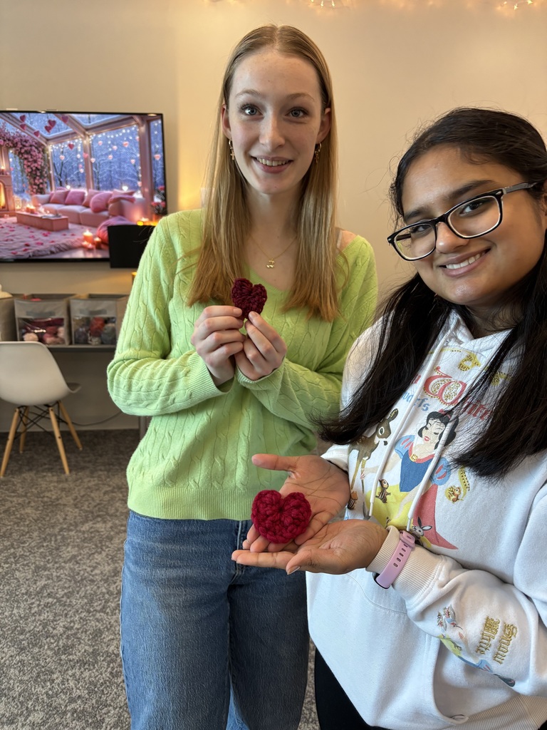 two students holding crochet hearts