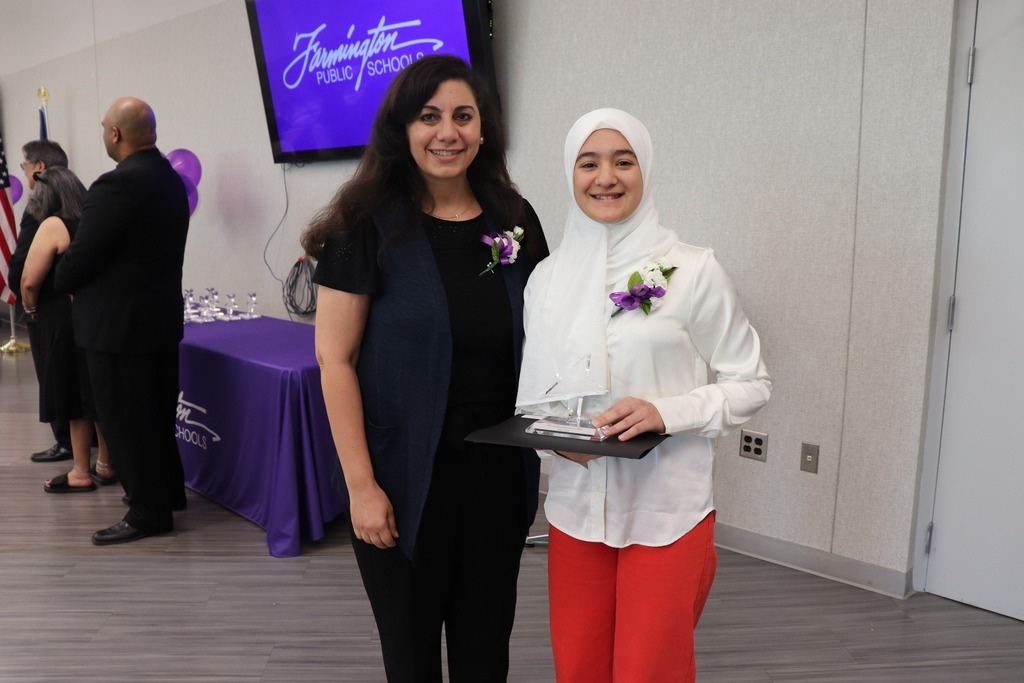Female staff member poses with female student holding her award.