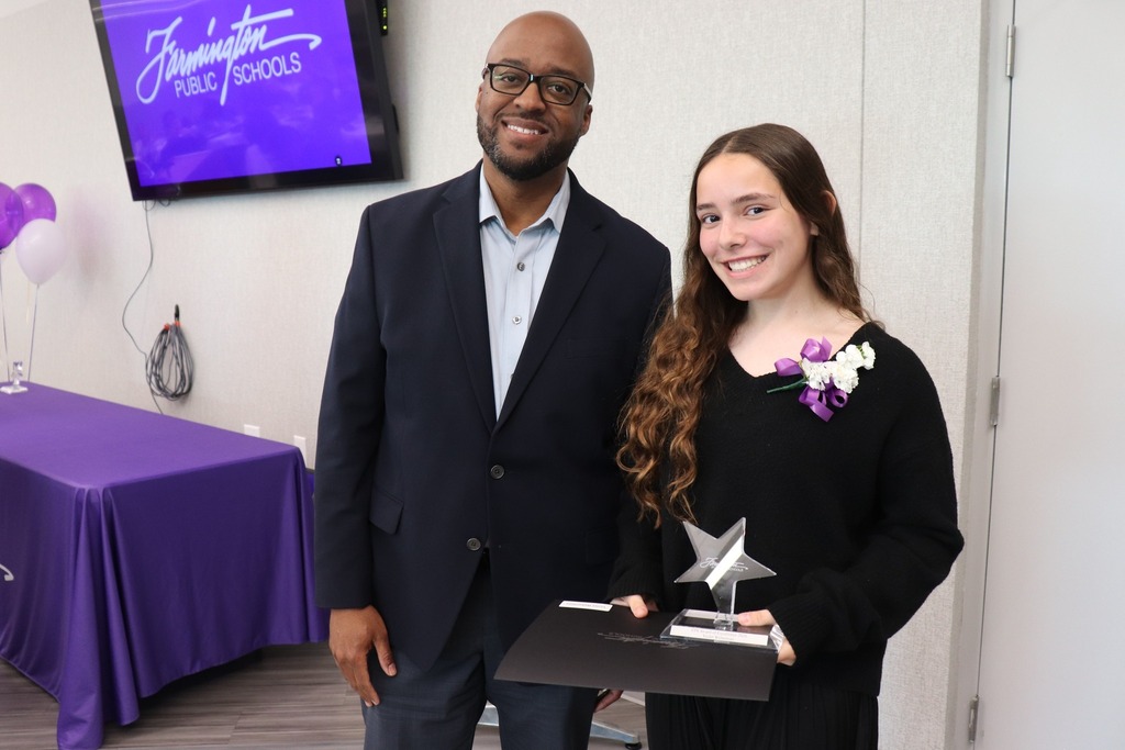 Male staff member poses with a female student holding her award.