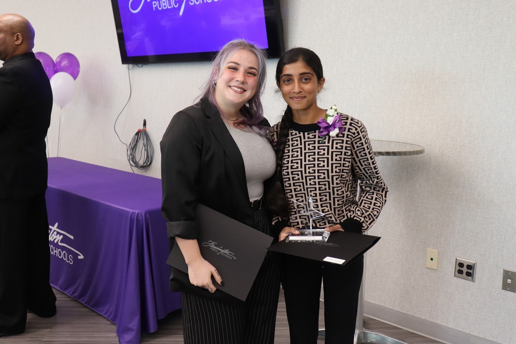 Female student holds her award and poses with an adult woman.