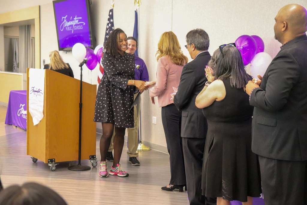 Staff and community leaders on stage shaking hands during the award banquet.