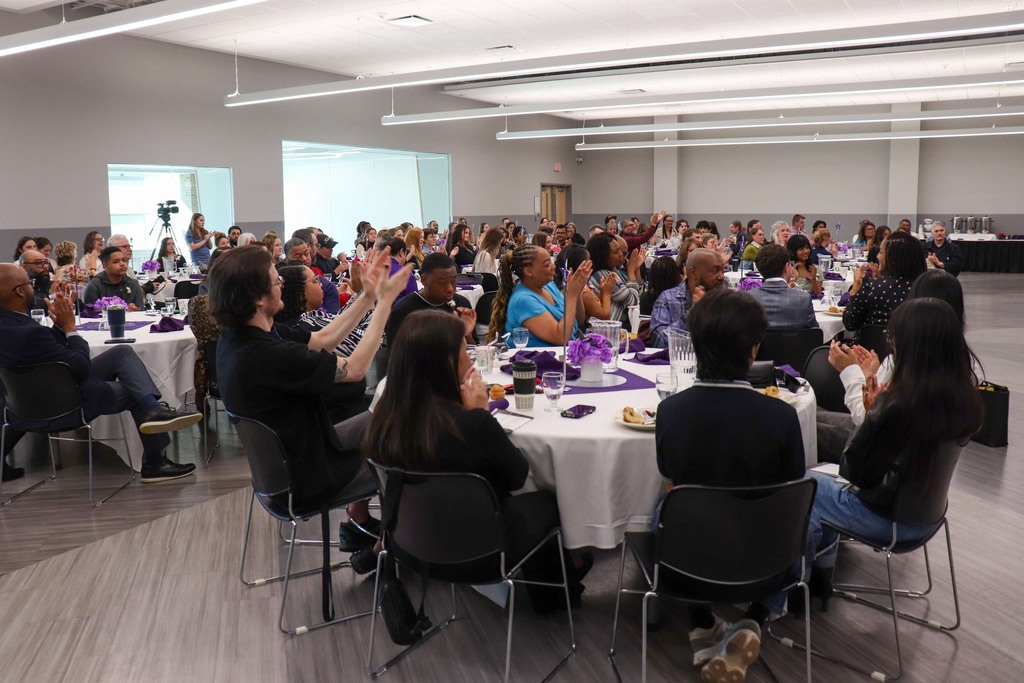 Photo of a diverse crowd of staff and students seated at large round banquet tables.
