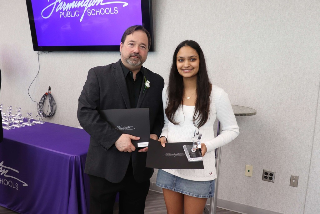 Male staff member poses with female student holding her award.