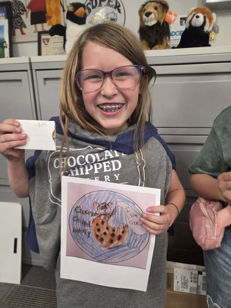 Student holding up her winning artwork and award.