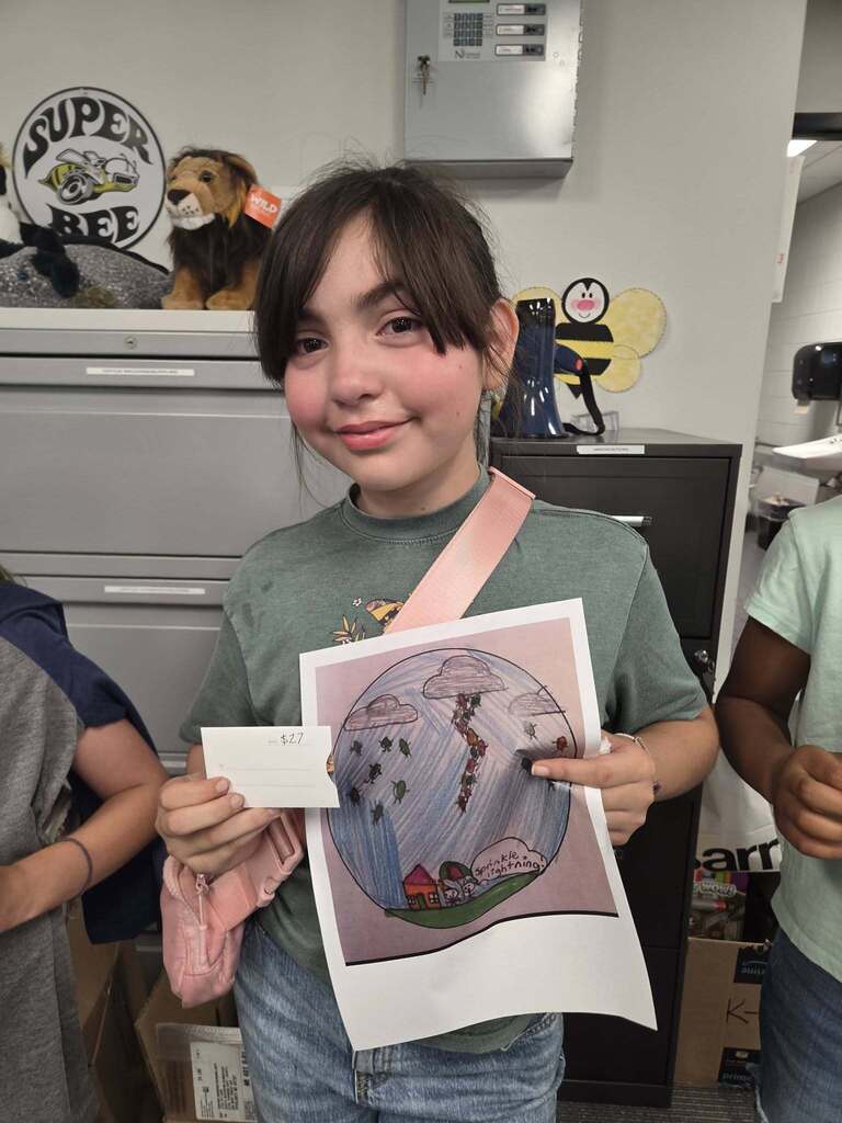 Student holding up her winning artwork and awarded gift card.