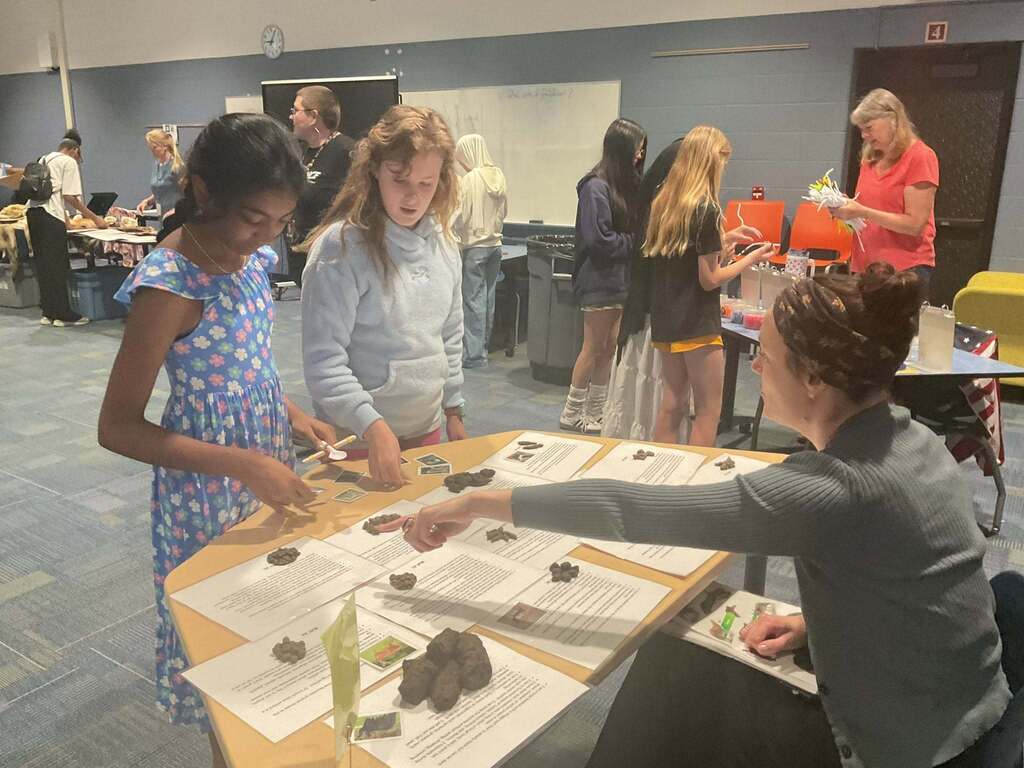 Students at another STEM Sampler table are reading instructions and browsing materials.