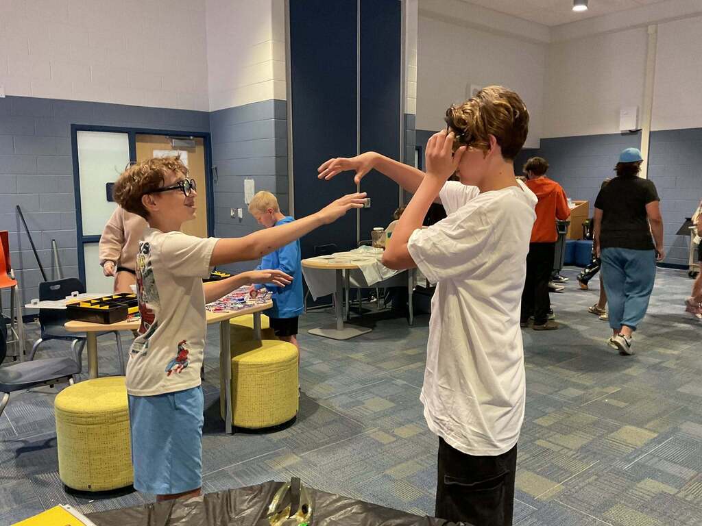 Two East Middle boys in STEM class trying on goggles.