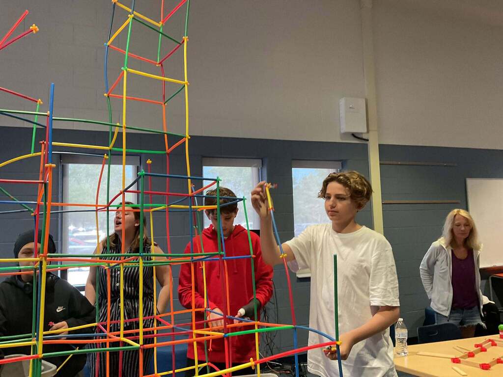 East Middle student builds a large STEM structure using colorful stick-like figures.