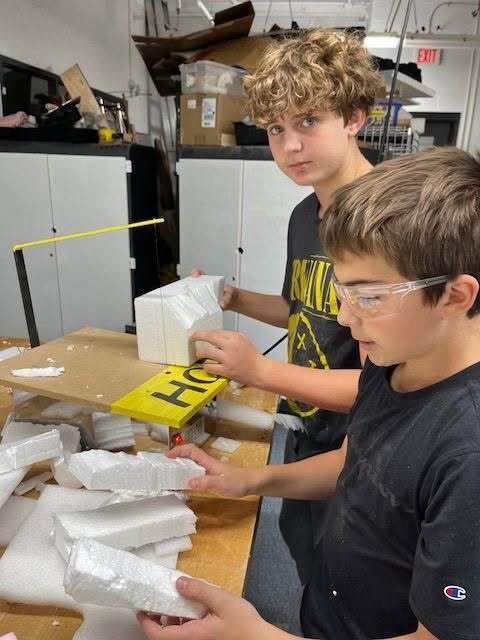 Two students work side by side holding pieces of styrofoam.