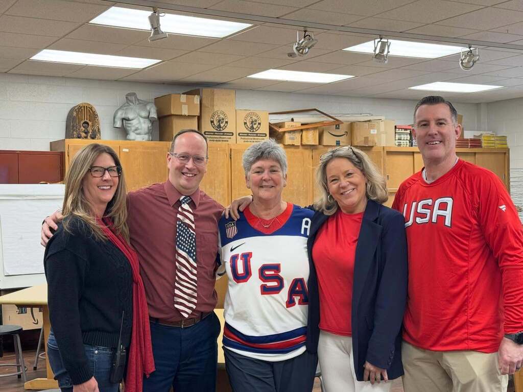 Group of people standing arm in arm wearing patriotic gear.