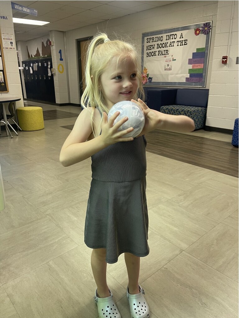 A student holding her prize out of the claw machine with an excited face